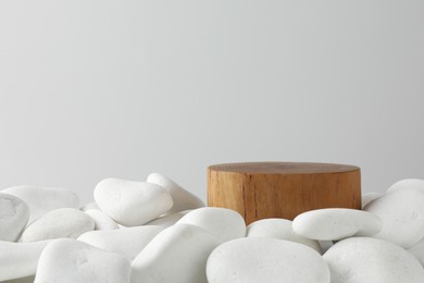 Photo of Presentation for product. Wooden podium and white pebbles on light background. Space for text