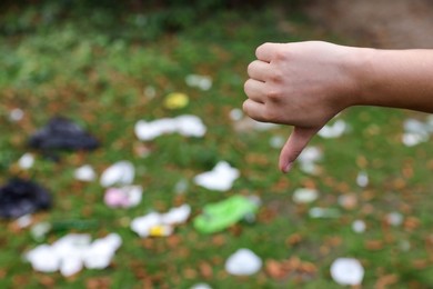 Photo of Woman showing thumb down in park, closeup with space for text. Garbage collection