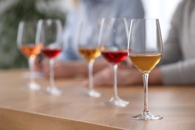 Photo of Different sorts of wine in glasses prepared for tasting and sommeliers at wooden table indoors, closeup