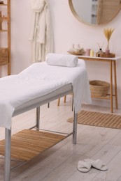 Photo of Comfortable massage table with clean towels in spa center