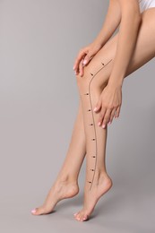 Epilation guide - how to remove hair in proper direction. Woman with drawn lines and arrows on her beautiful smooth legs against light grey background
