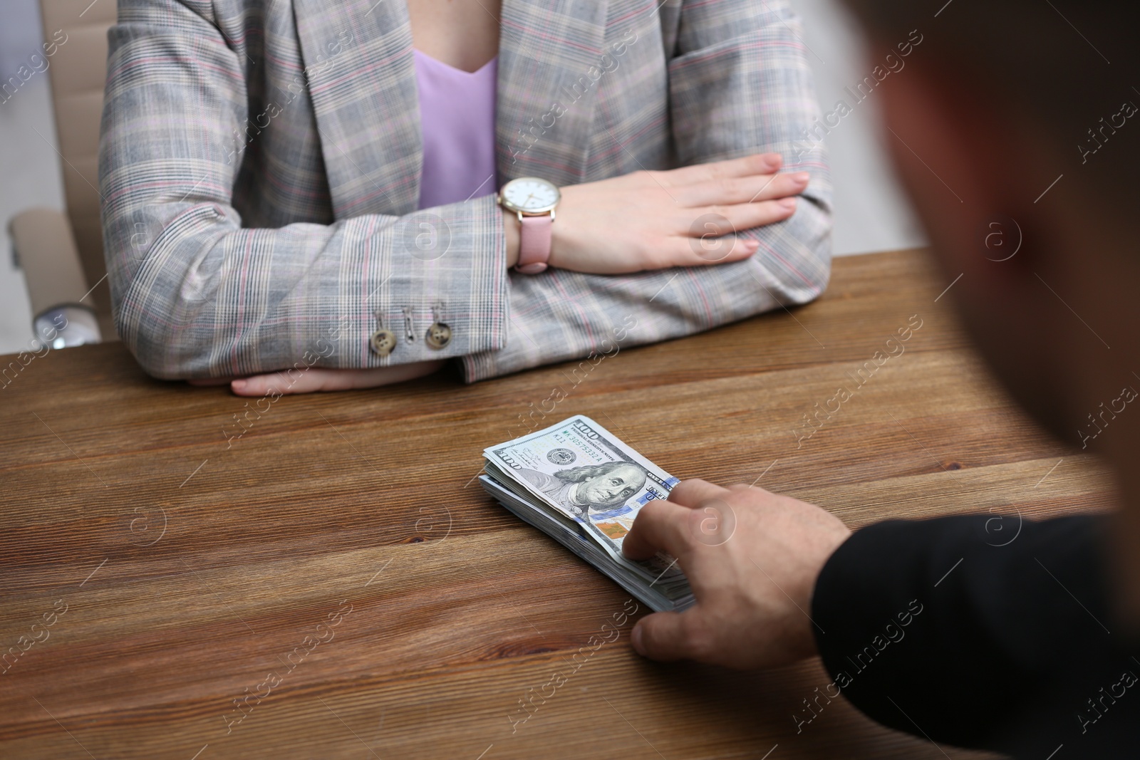 Photo of Man offering bribe money to woman at table, closeup
