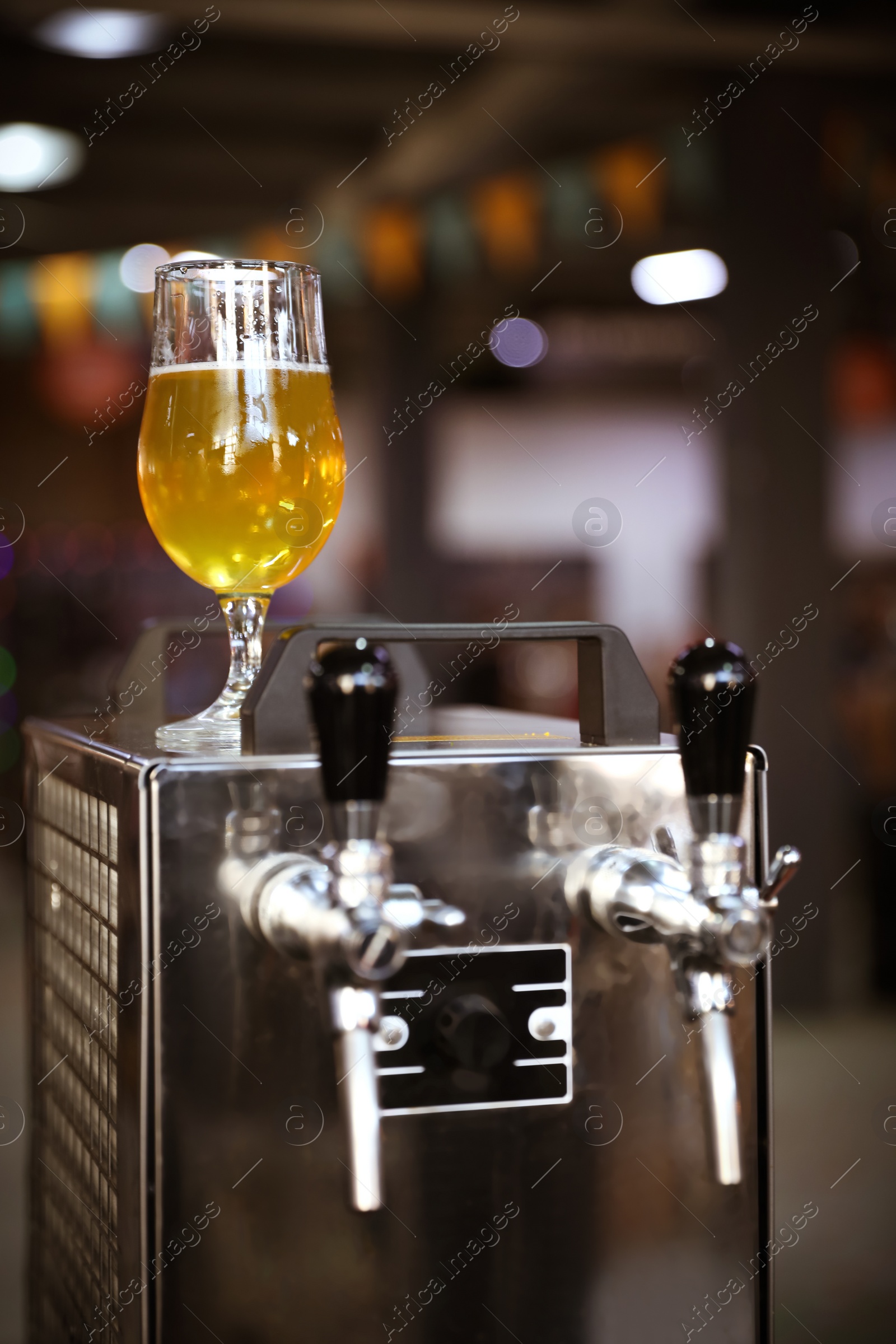 Photo of Glass of refreshing beer on cooling machine in pub