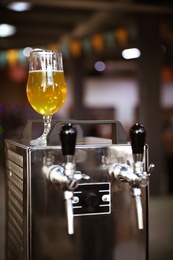 Glass of refreshing beer on cooling machine in pub