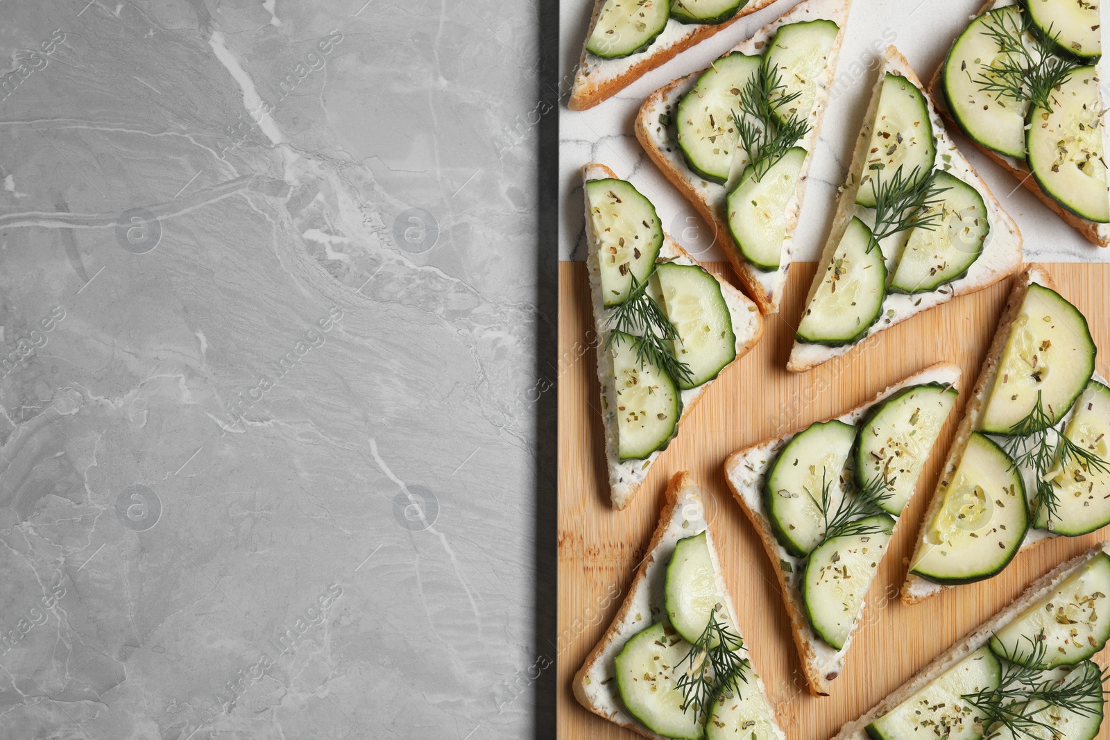 Photo of Tasty sandwiches with cream cheese, cucumber and dill on grey marble table, flat lay. Space for text