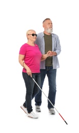 Mature man helping blind person with long cane on white background