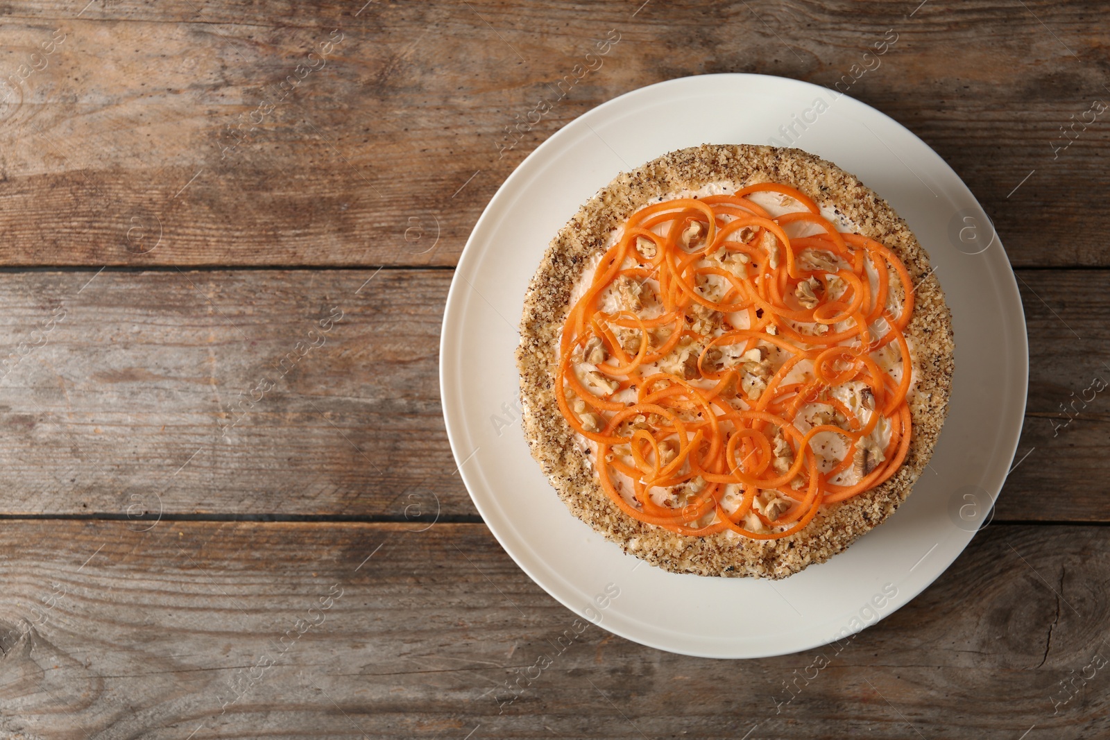 Photo of Dish with delicious carrot cake on wooden background, top view. Space for text