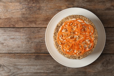 Dish with delicious carrot cake on wooden background, top view. Space for text