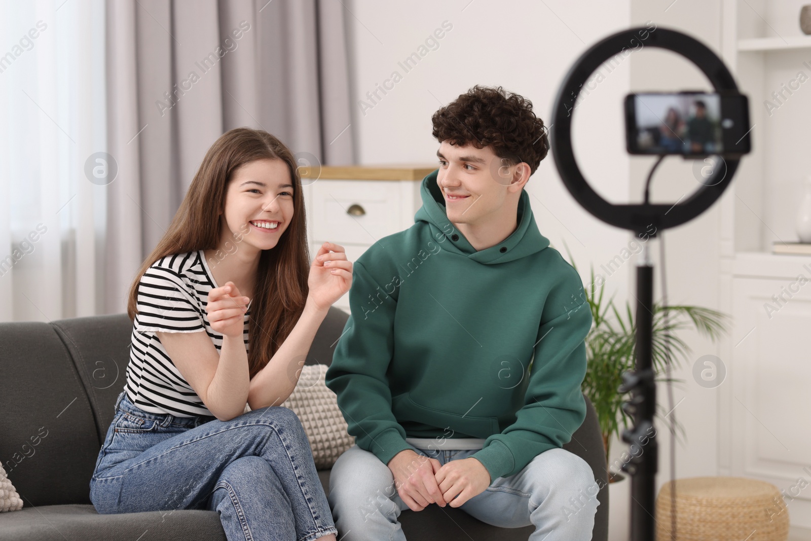 Photo of Smiling teenage bloggers talking while streaming at home