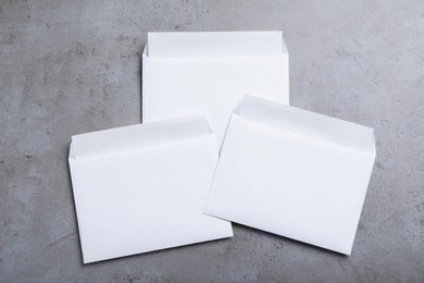 Photo of Simple white paper envelopes on grey table, flat lay