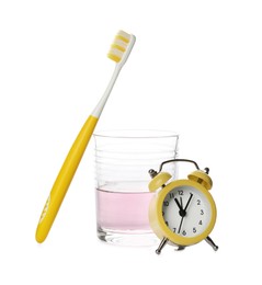 Mouthwash, toothbrush and alarm clock on white background