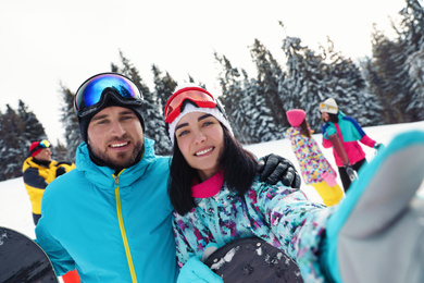 Photo of Couple taking selfie on snowy hill. Winter vacation