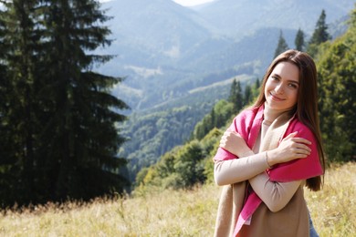 Young woman in mountains on sunny day, space for text