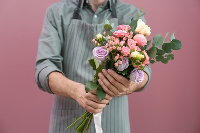 Male florist with beautiful bouquet on color background