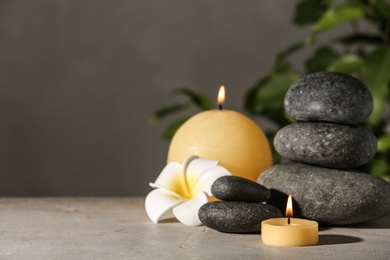 Photo of Composition with candles and spa stones on grey table. Space for text