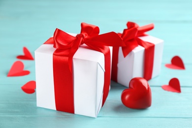 Beautiful gift boxes and red heart on turquoise wooden table, closeup. Valentine's Day celebration