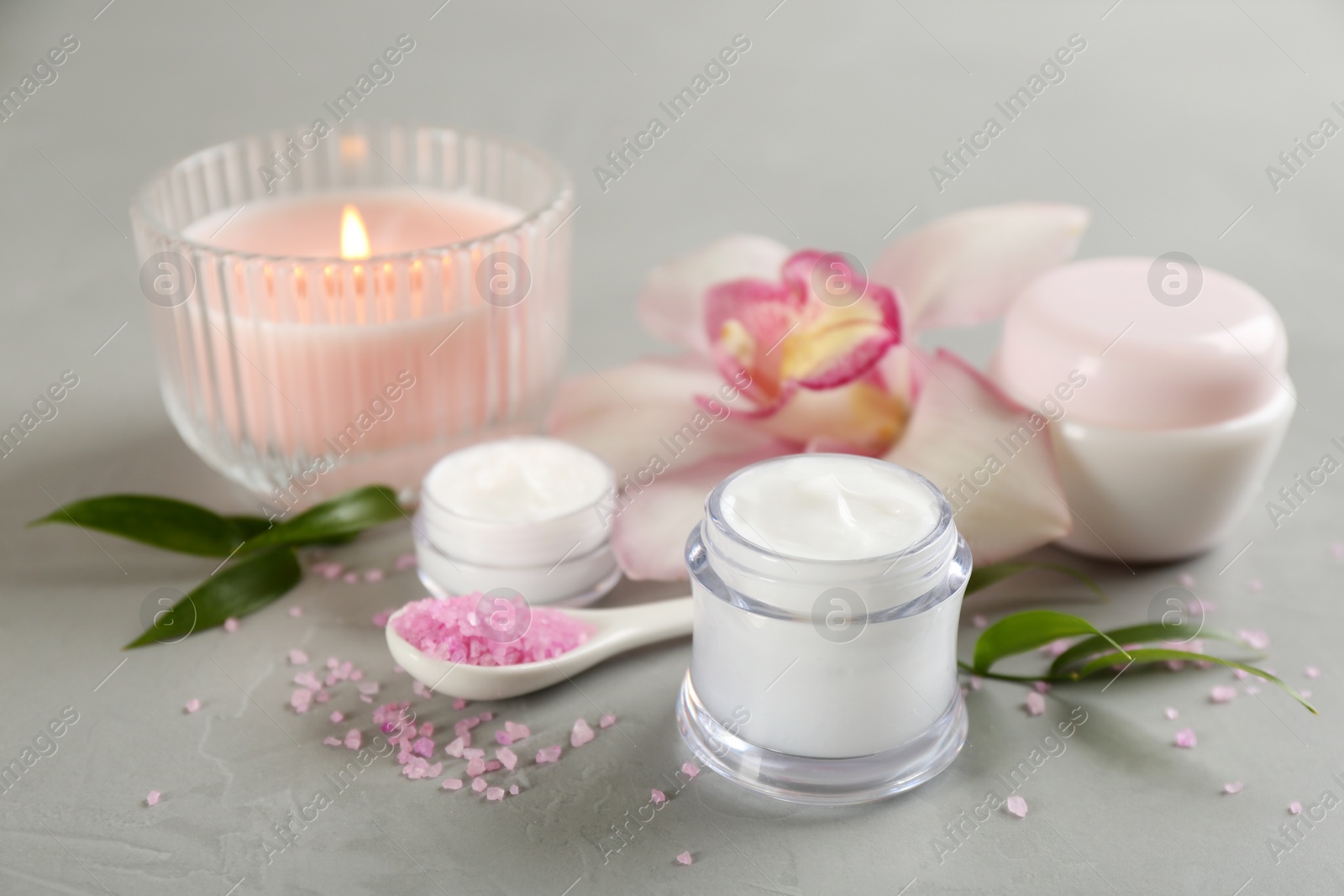 Photo of Beautiful spa composition with cosmetic products, flowers and candle on light grey table