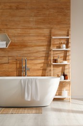 Photo of Bathroom interior with white tub and decor near wooden wall