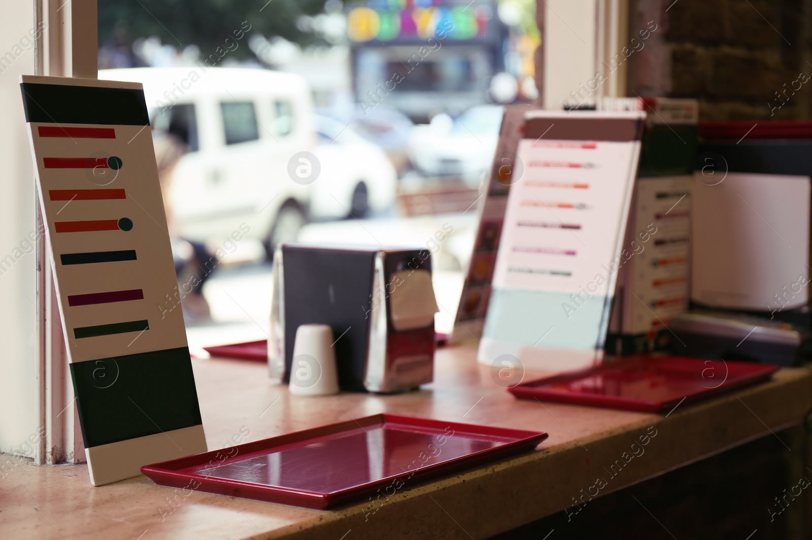 Photo of Menu and empty tray on table near window in cafe