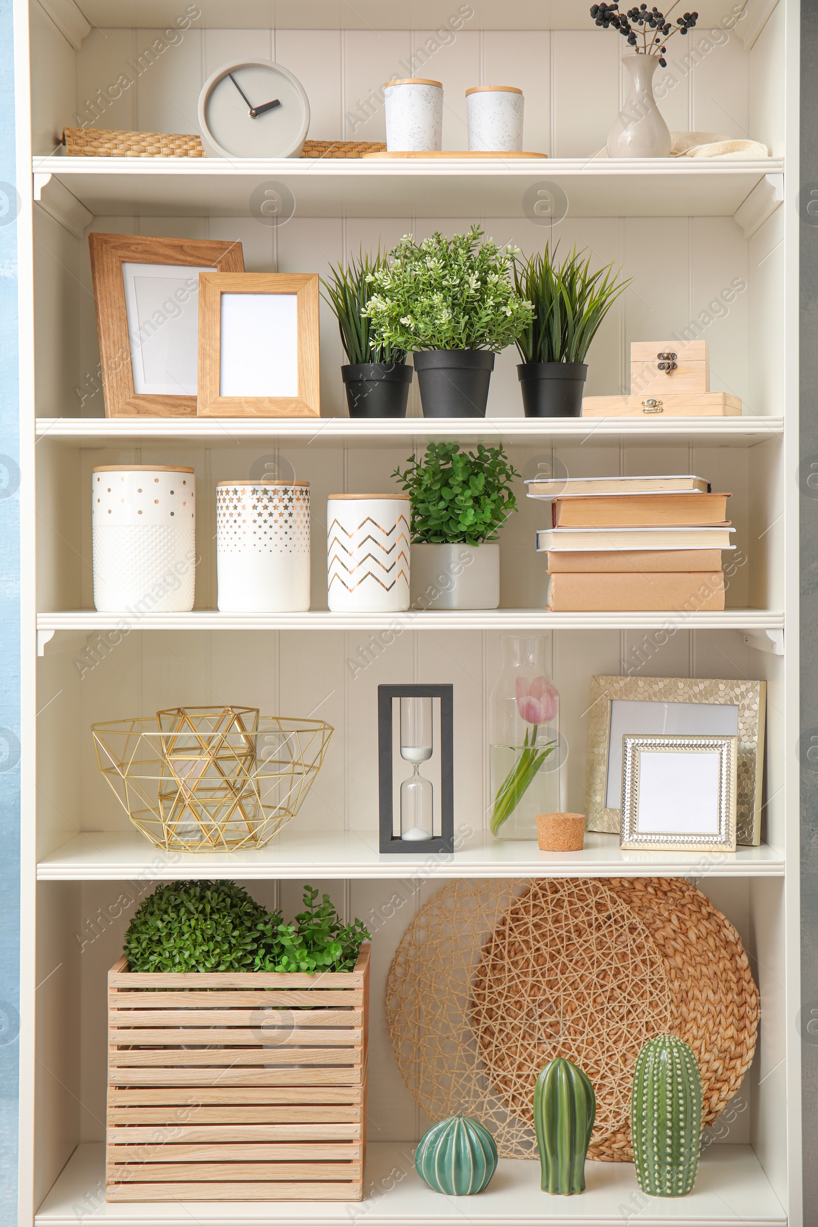 Photo of White shelving unit with plants and different decorative stuff