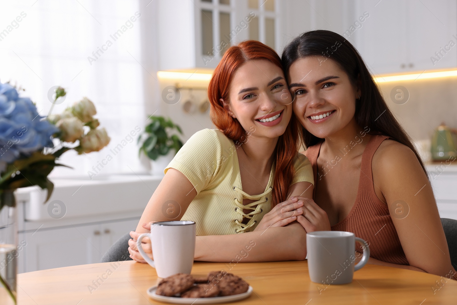 Photo of Portrait of happy young friends at table in kitchen