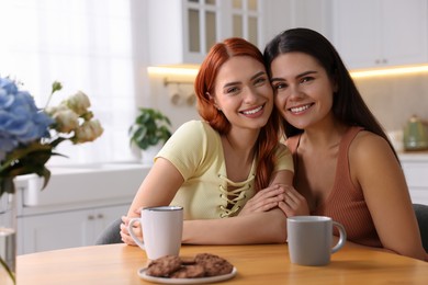 Photo of Portrait of happy young friends at table in kitchen