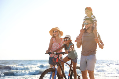 Happy family with bicycle on beach near sea