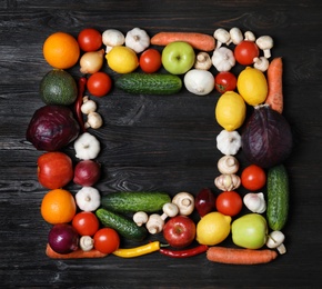 Frame made of fresh delicious vegetables and fruits on wooden table, flat lay. Space for text