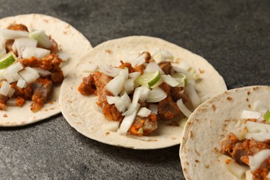 Photo of Delicious tacos with vegetables, meat and lime on grey textured table, closeup