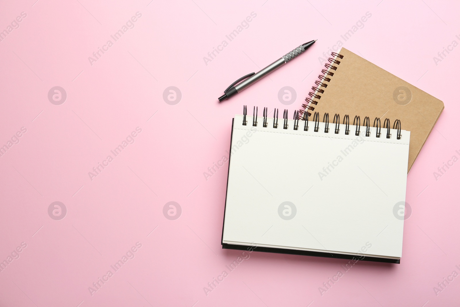 Photo of Notebooks and pen on pink background, top view. Space for text