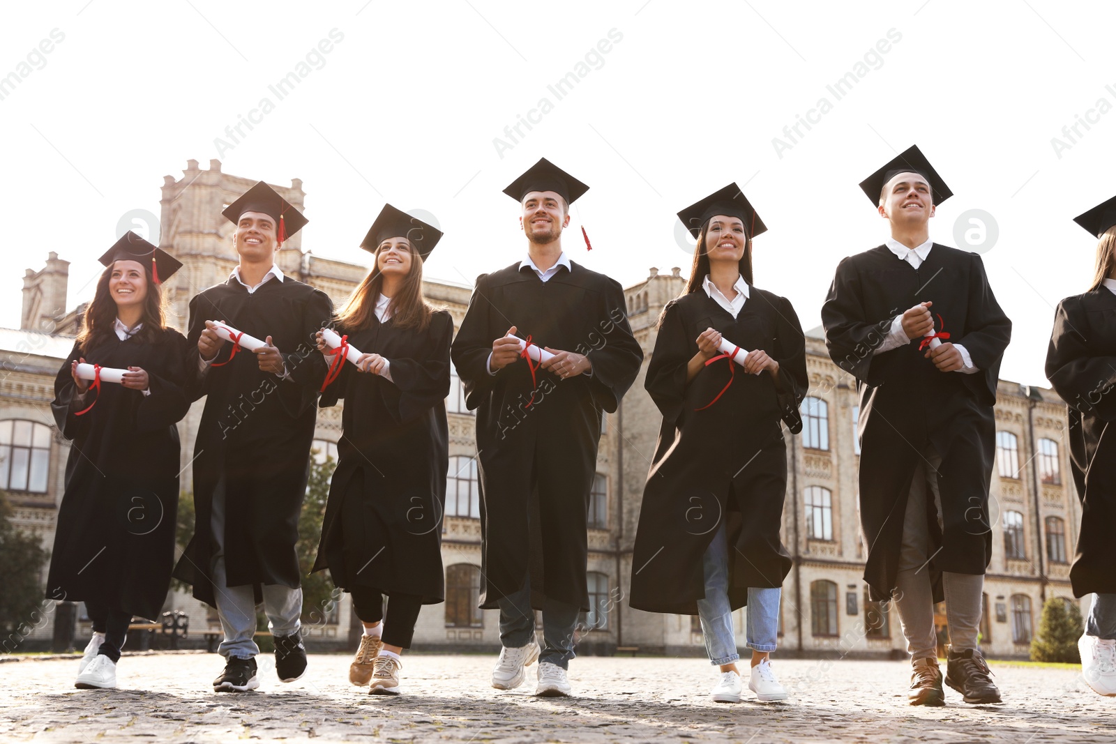 Photo of Happy students with diplomas outdoors. Graduation ceremony