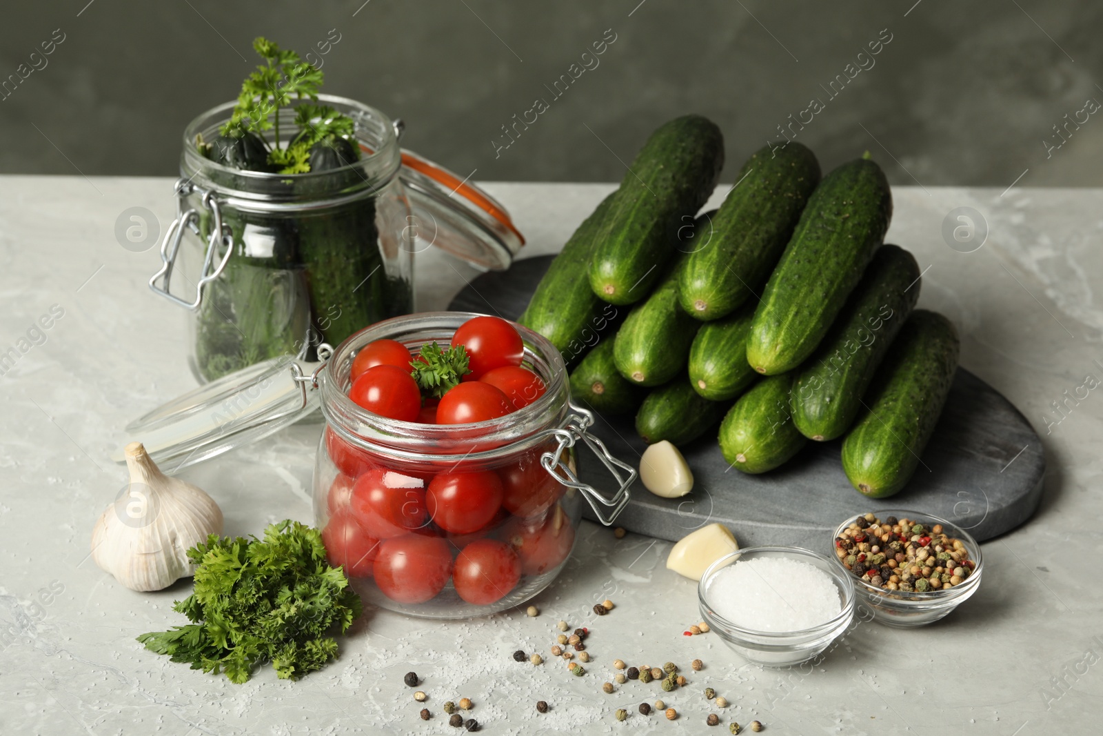 Photo of Pickling jars with fresh ripe vegetables and spices on grey table