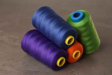 Photo of Set of color sewing threads on grey table, closeup