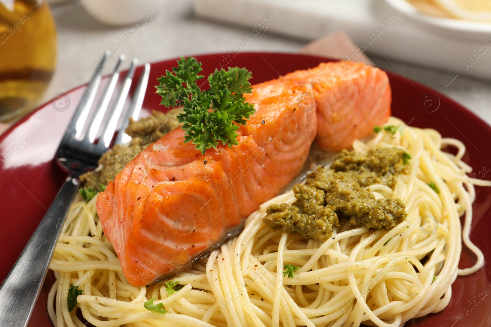 Photo of Delicious spaghetti with salmon and pesto sauce on plate, closeup