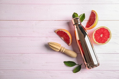 Photo of Flat lay composition with grapefruit, bottle of juice and space for text on wooden background