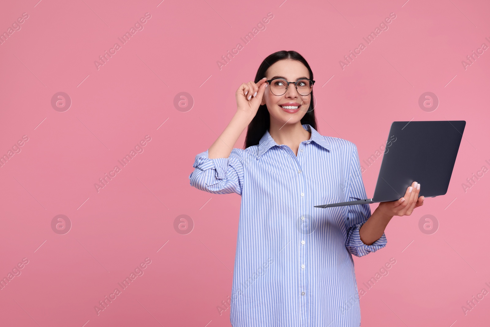 Photo of Happy woman with laptop on pink background, space for text