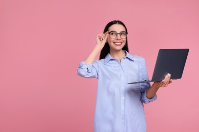 Happy woman with laptop on pink background, space for text