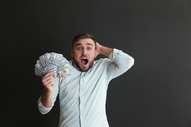 Photo of Portrait of emotional young man with money on grey background