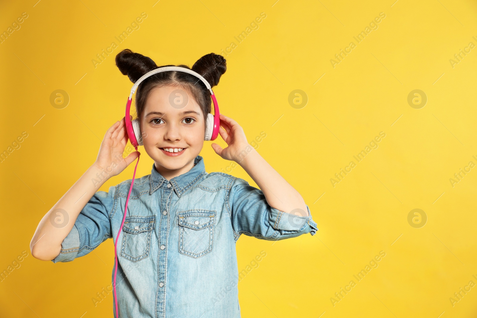 Photo of Cute girl enjoying music in headphones on color background. Space for text