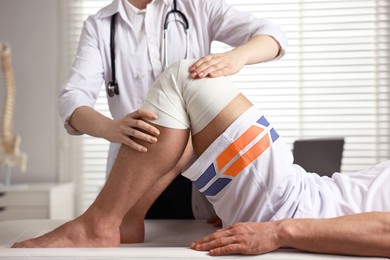Sports injury. Doctor examining patient's knee in hospital, closeup