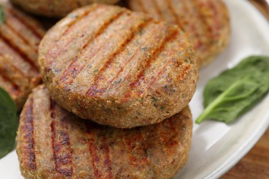 Tasty grilled vegan cutlets and spinach on plate, closeup