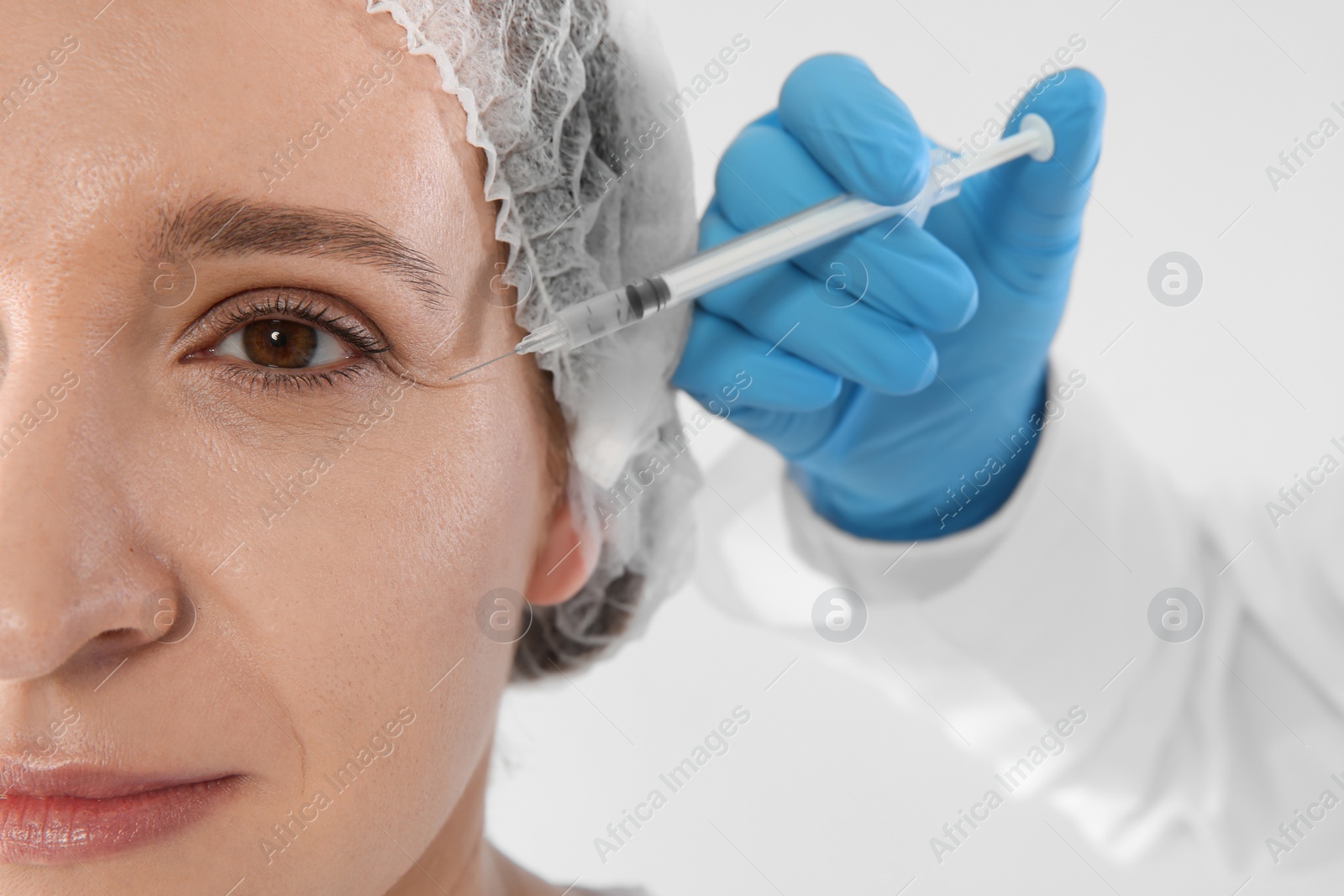 Photo of Woman getting facial injection on white background, closeup. Cosmetic surgery concept