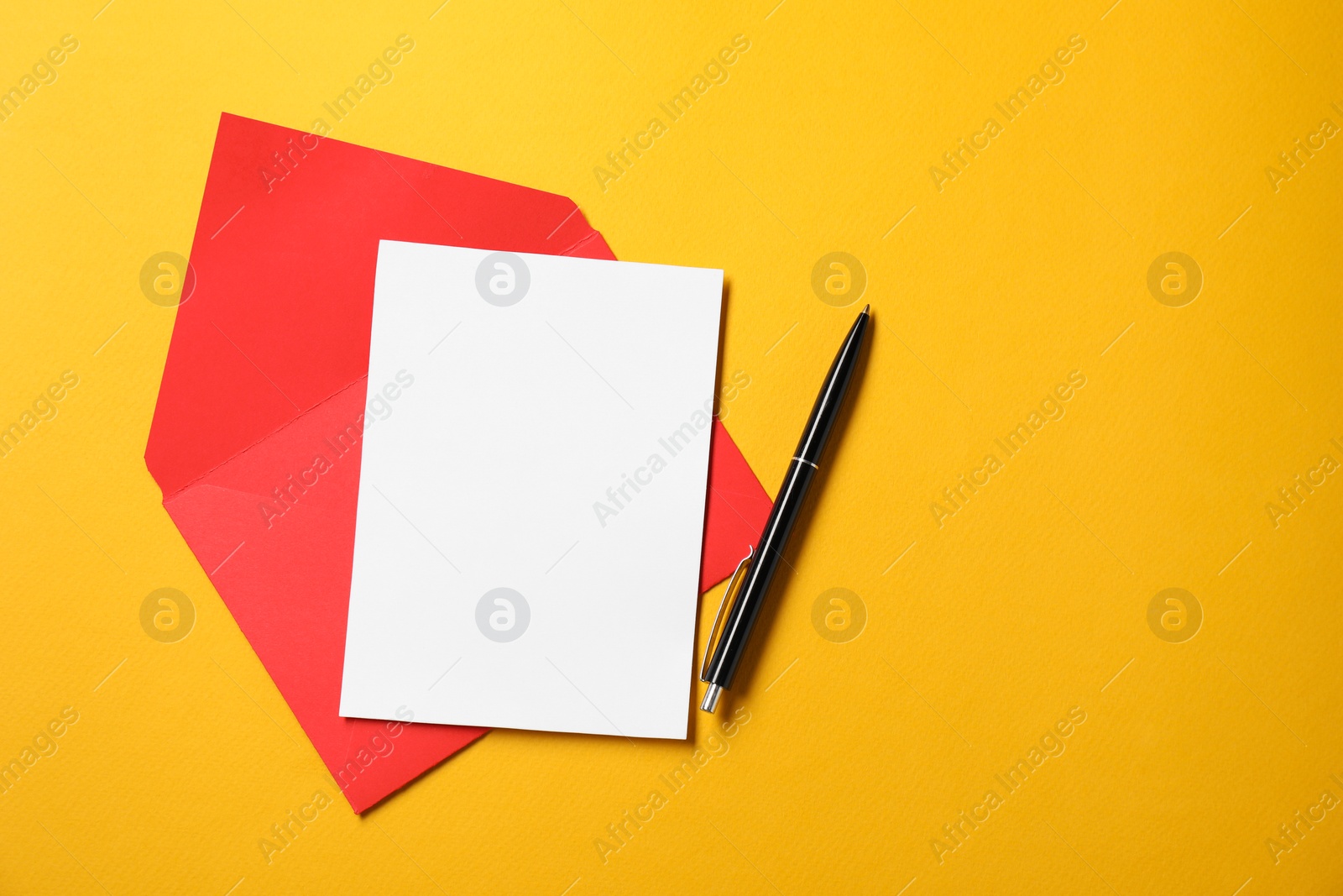 Photo of Blank sheet of paper, letter envelope and pen on orange background, top view. Space for text