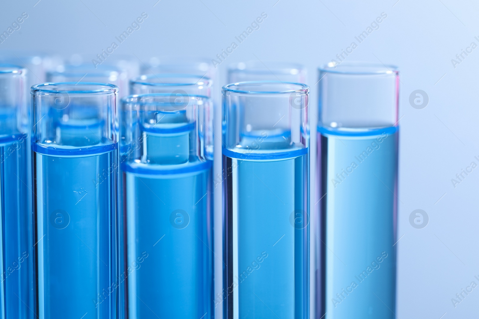 Photo of Test tubes with reagents on light blue background, closeup. Laboratory analysis