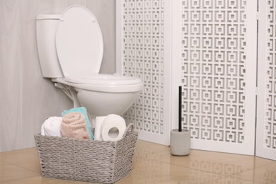 Photo of White toilet bowl near folding screen in bathroom