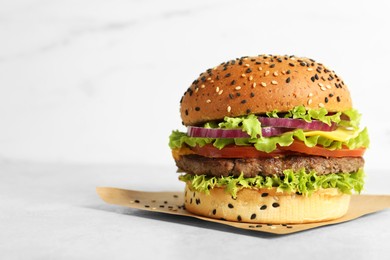 Photo of Burger with delicious patty on light table, space for text