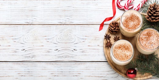 Image of Delicious Christmas cocktail with liqueur on white wooden table, flat lay with space for text. Banner design