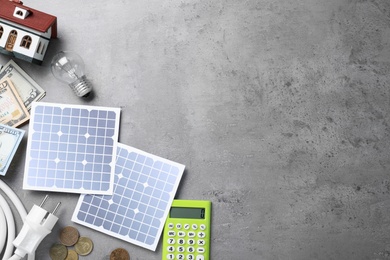 Photo of Flat lay composition with solar panels and money on grey table. Space for text