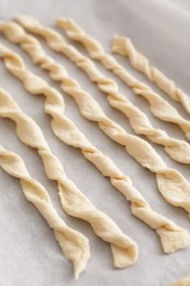 Photo of Homemade breadsticks on baking sheet, closeup. Cooking traditional grissini