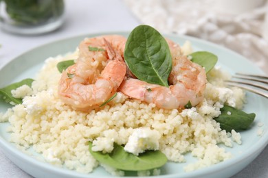 Photo of Delicious couscous with shrimps and spinach served on white table, closeup